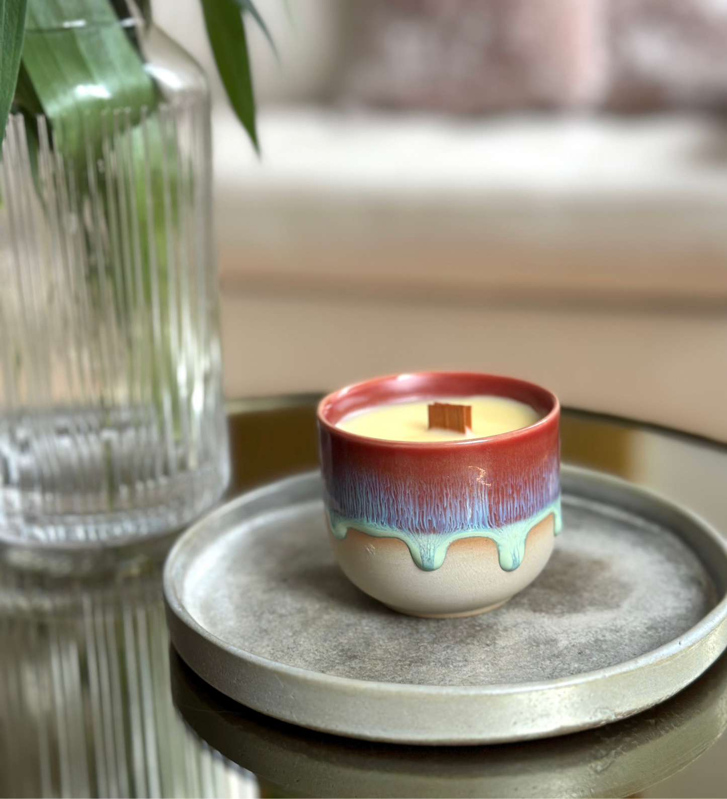Colorful ceramic wood wick candle on a gray tray with a blurred background