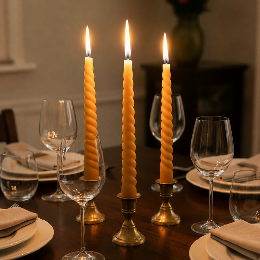 Dining table set with candles, glasses, and cutlery in a warm setting.
