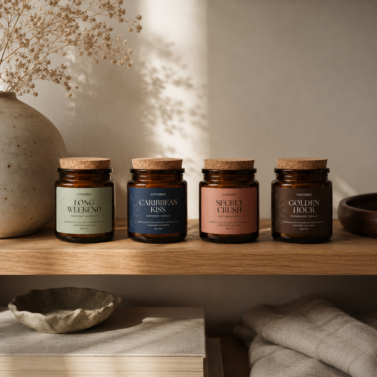 Four candles with labeled names on a wooden shelf with a neutral background