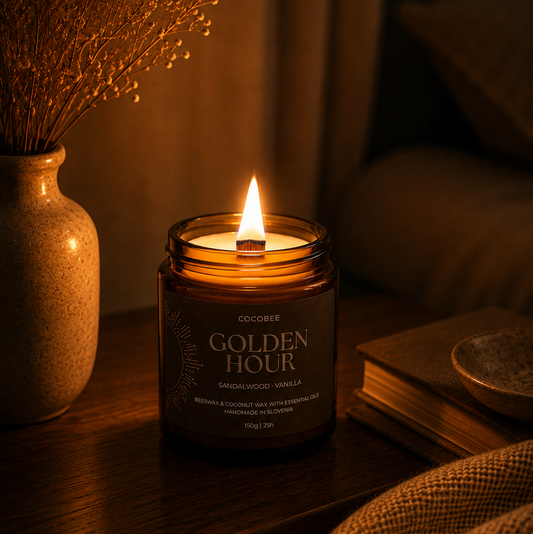Candle labeled 'Golden Hour' on a wooden surface with a vase of dried flowers and a book in the background.