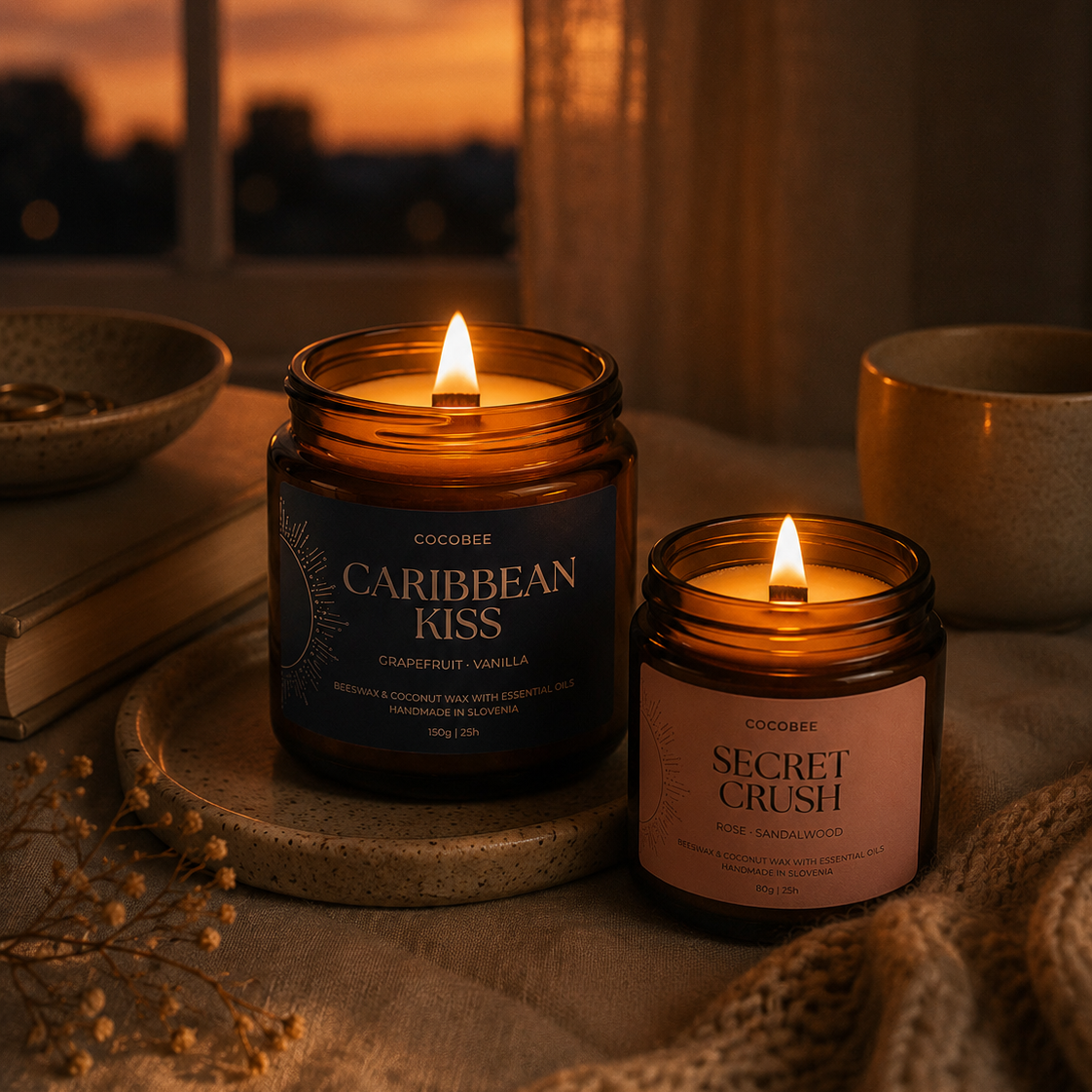 Two lit candles labeled 'Caribbean Kiss' and 'Secret Crush' on a surface with a warm, evening atmosphere.