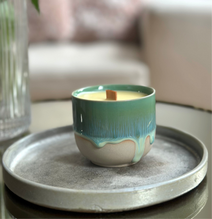 Ceramic wood wick candle in a decorative pot on a tray with a blurred background